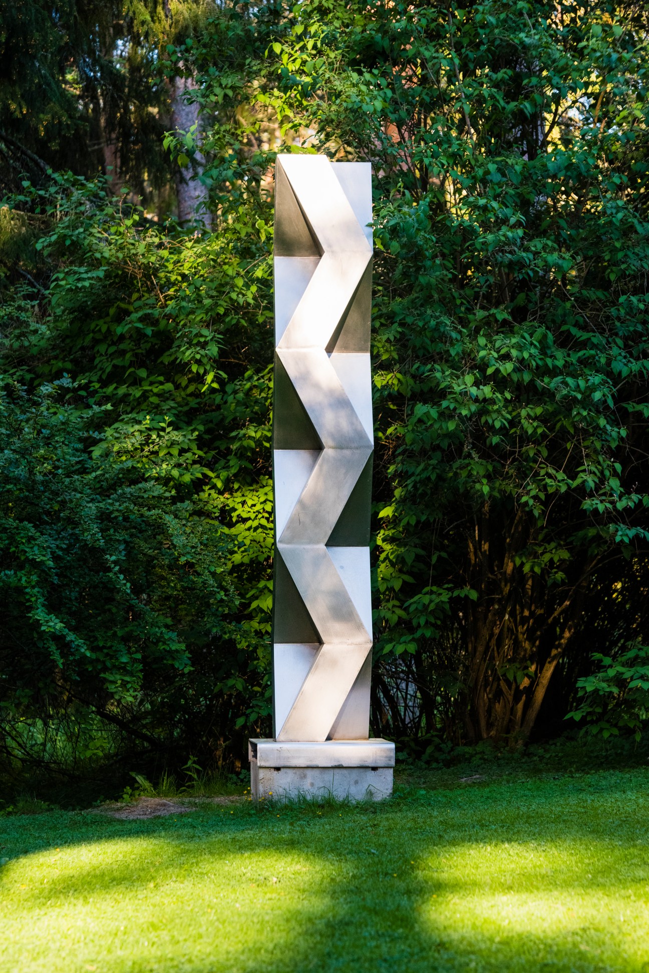 Modern white sculptural artwork displayed in a forest setting at the Ahlström Ironworks.