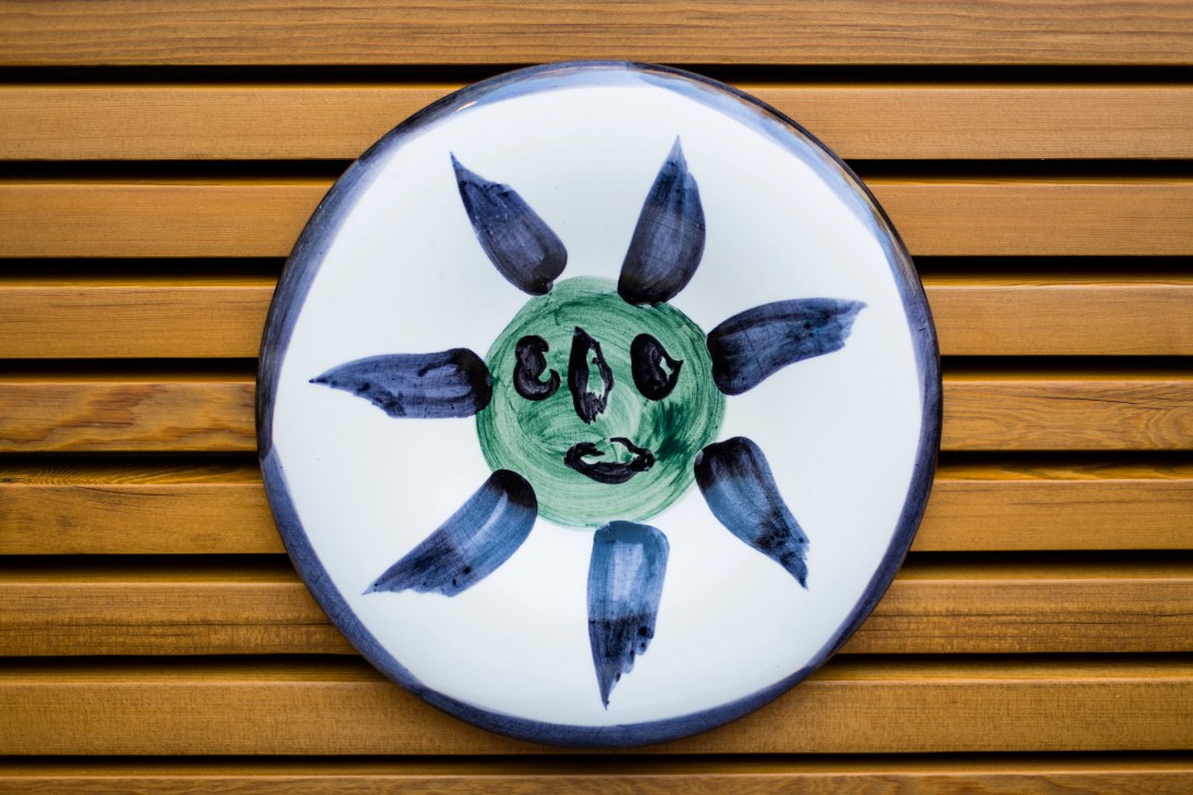 Ceramic plate featuring a stylized green face with blue horns and features by Picasso
