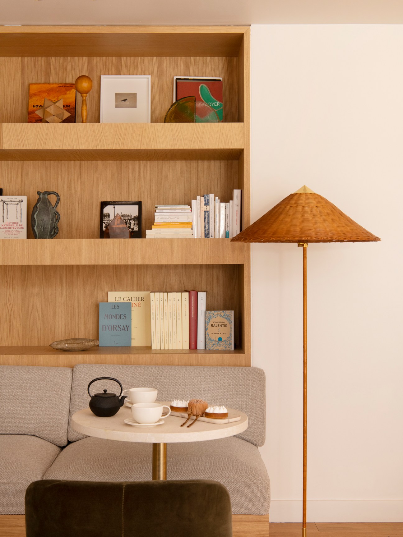 Hotel Nuage Paris interior reading nook with wooden built-in bookshelf, gray seating, and woven lampshade