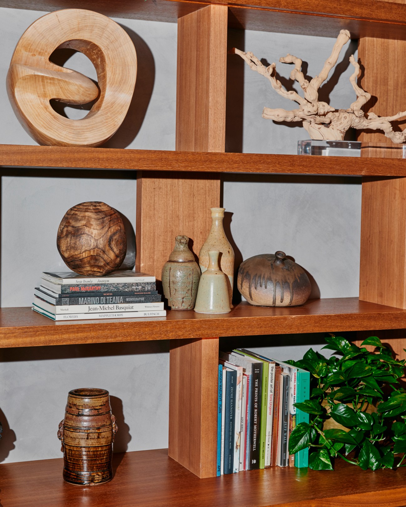 Wooden shelving displaying decorative objects including carved sculptures, pottery, books, and a small plant