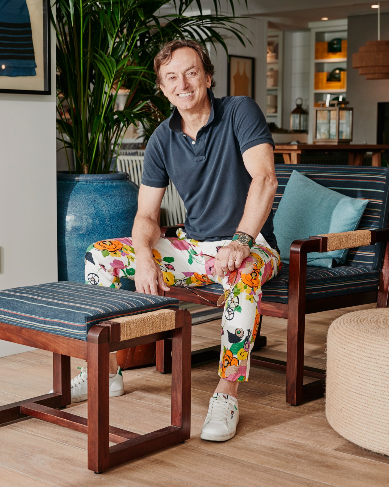 Nicolo Bini of Line Architecture sitting on striped upholstered furniture wearing colorful floral pants and navy polo shirt