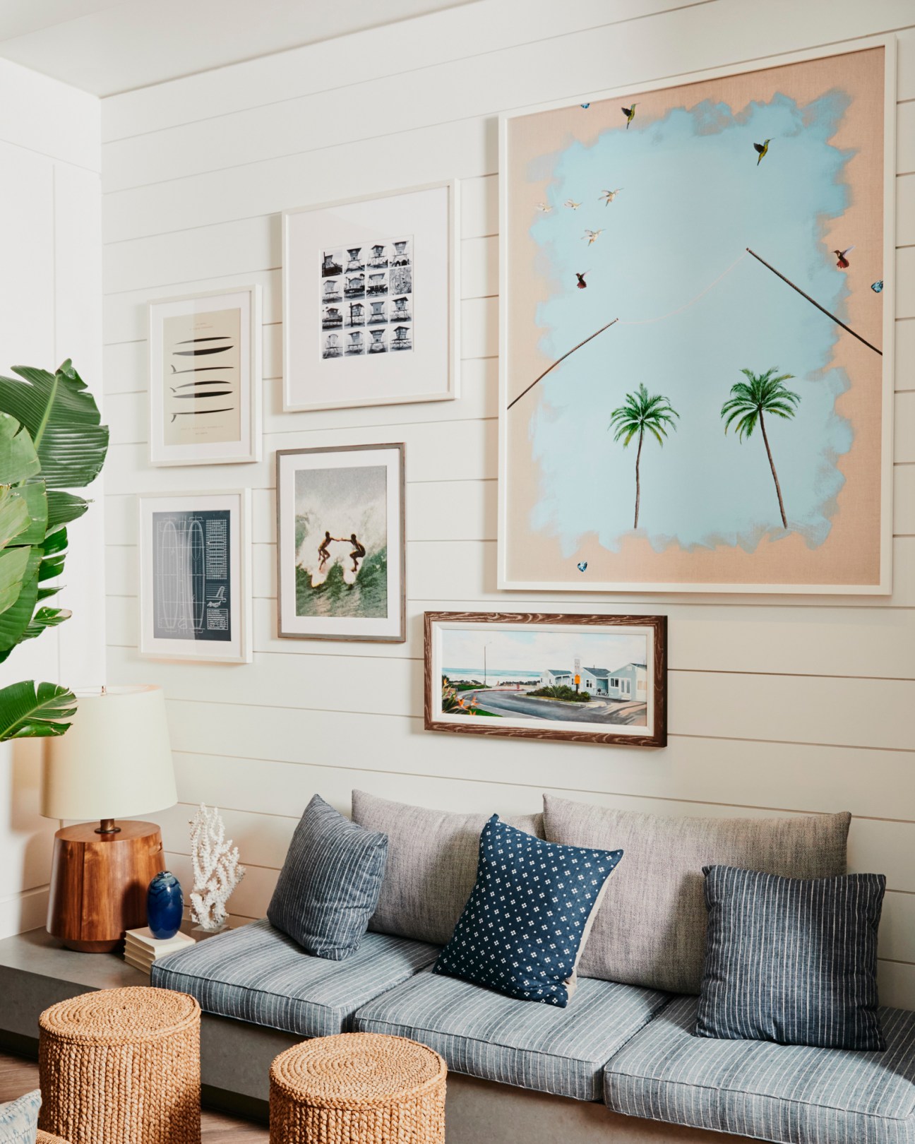 Modern hotel lobby seating area with gray sofa, patterned pillows, woven baskets, and gallery wall of framed artwork
