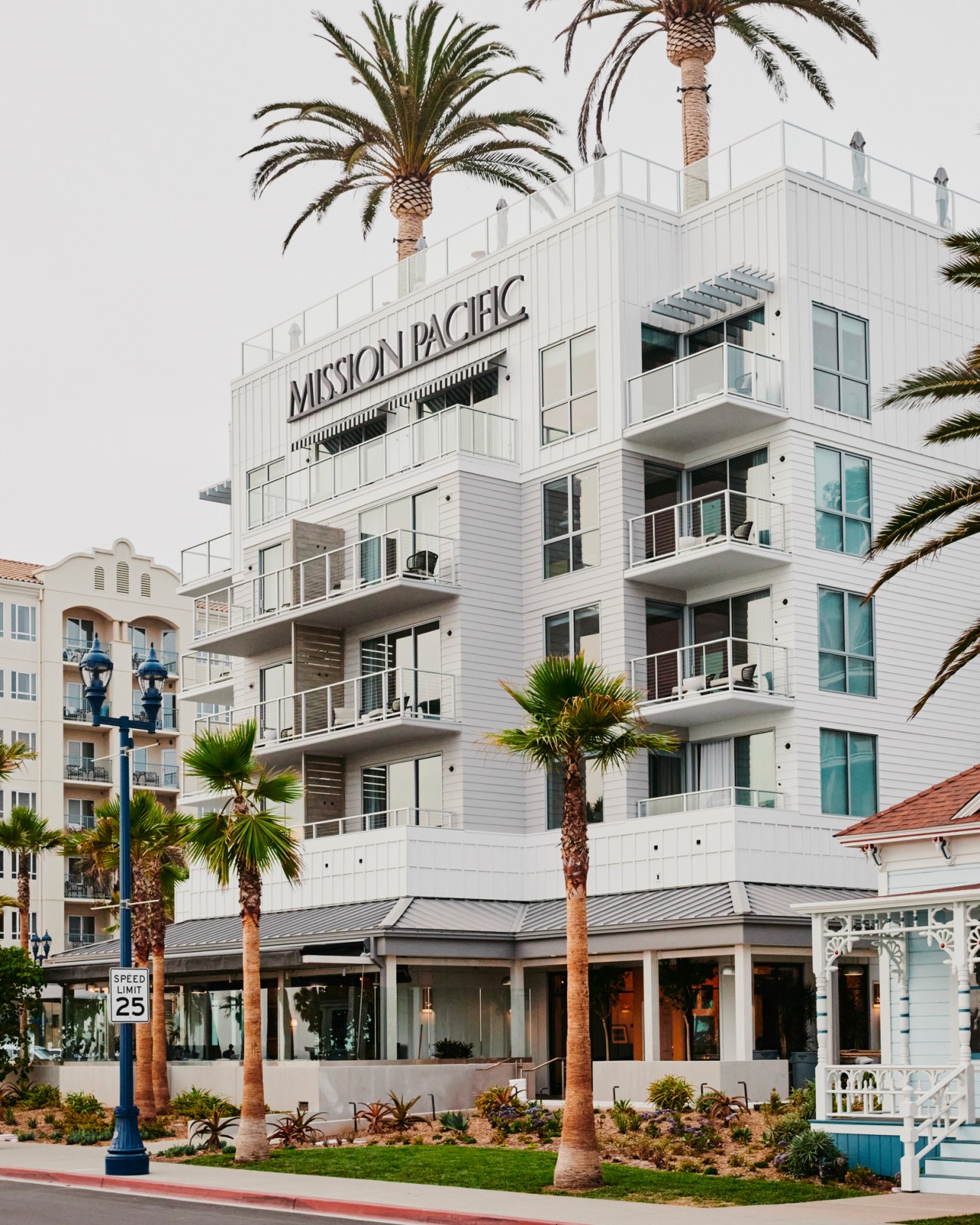 Mission Pacific hotel exterior with white wooden siding, multiple balconies, and palm trees in foreground
