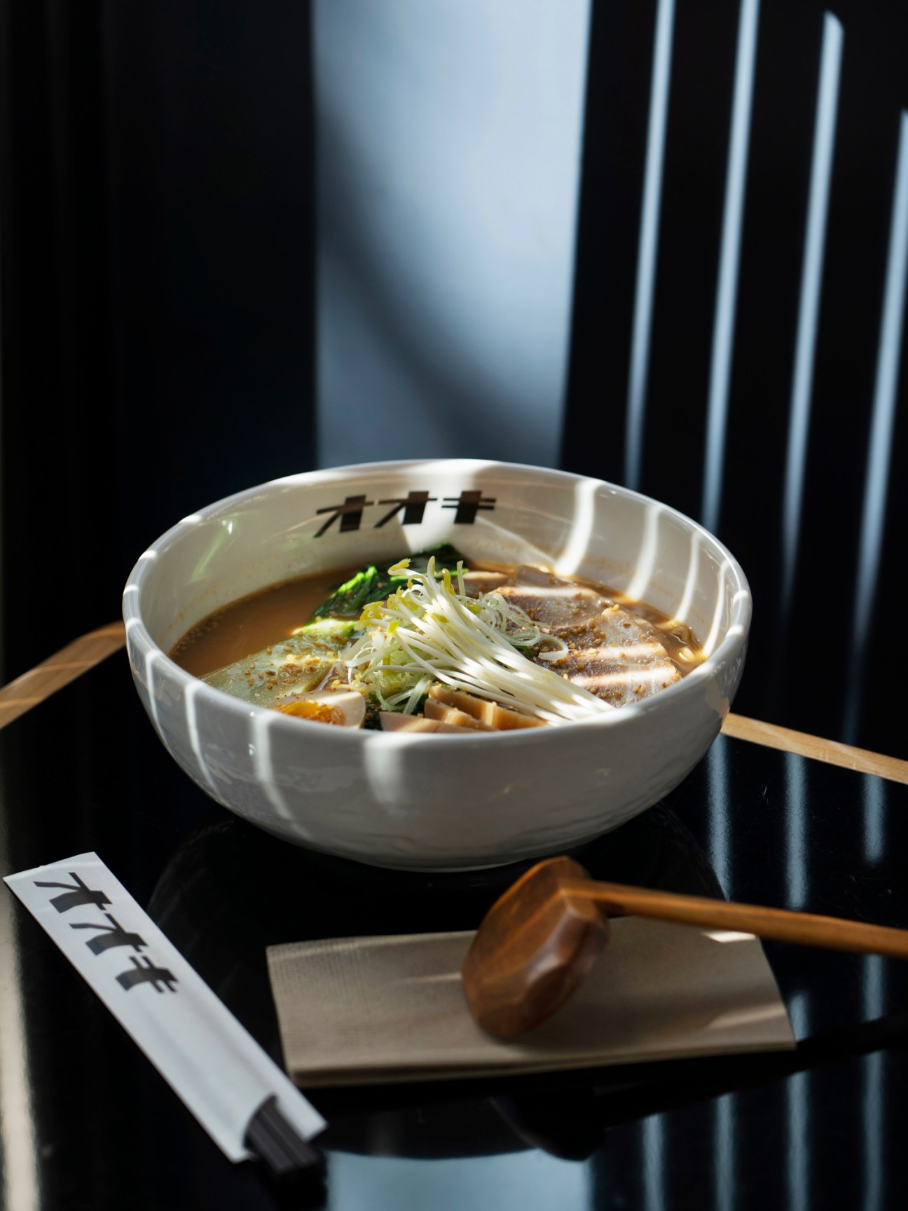 Bowl of miso ramen with pork, scallions and noodles in a white ceramic bowl with Ooki branding