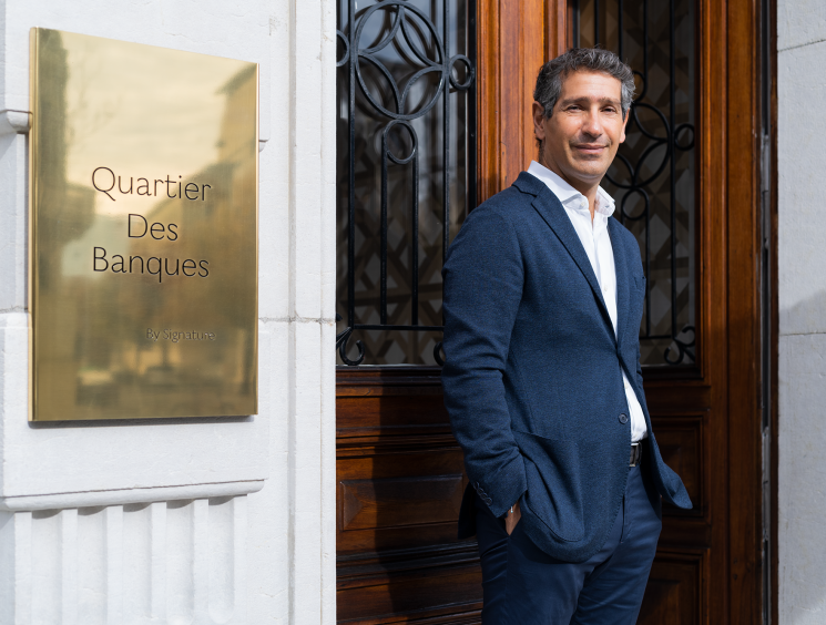 Man in a navy blazer standing outside the Quartier des Banques entrance.