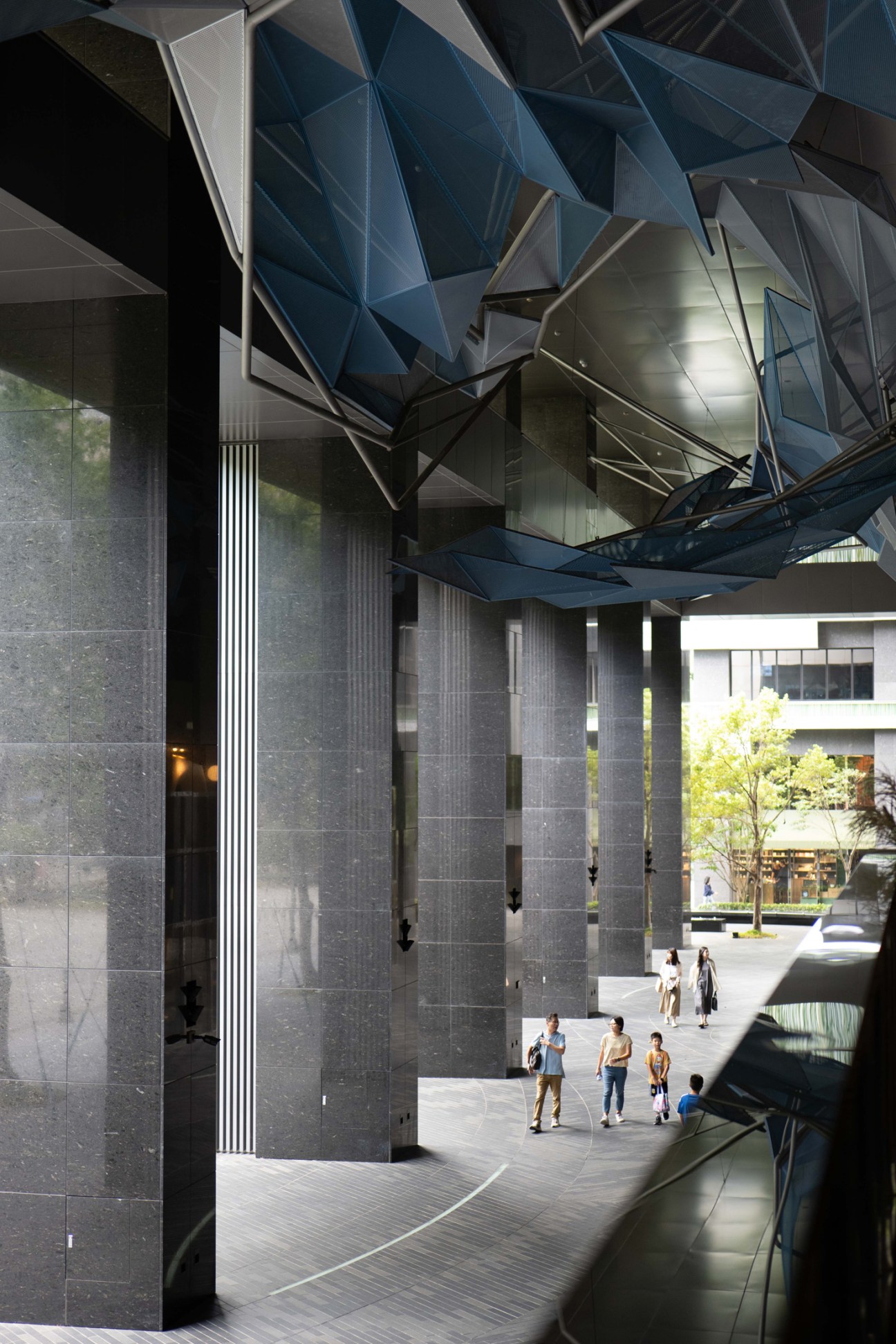 Noke shopping mall entrance in Taipei with geometric blue overhead canopy and dark stone columns.