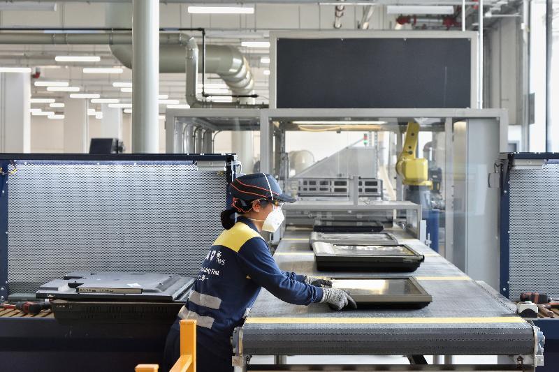 Worker in protective gear and mask operating industrial conveyor belt machinery in modern facility
