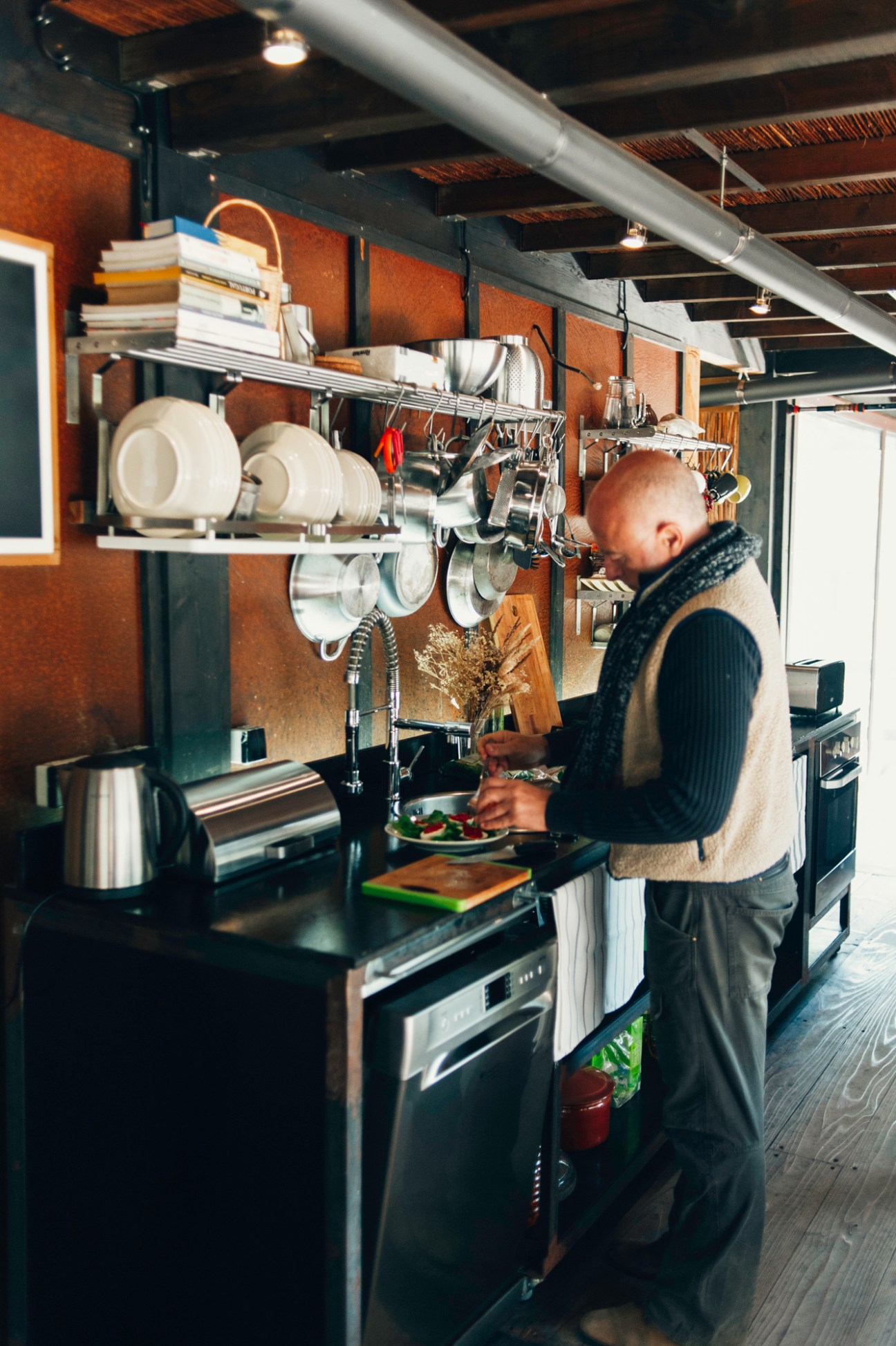 Francesco Ippolito preparing lunch in his modern kitchen with industrial shelving and stainless steel appliances