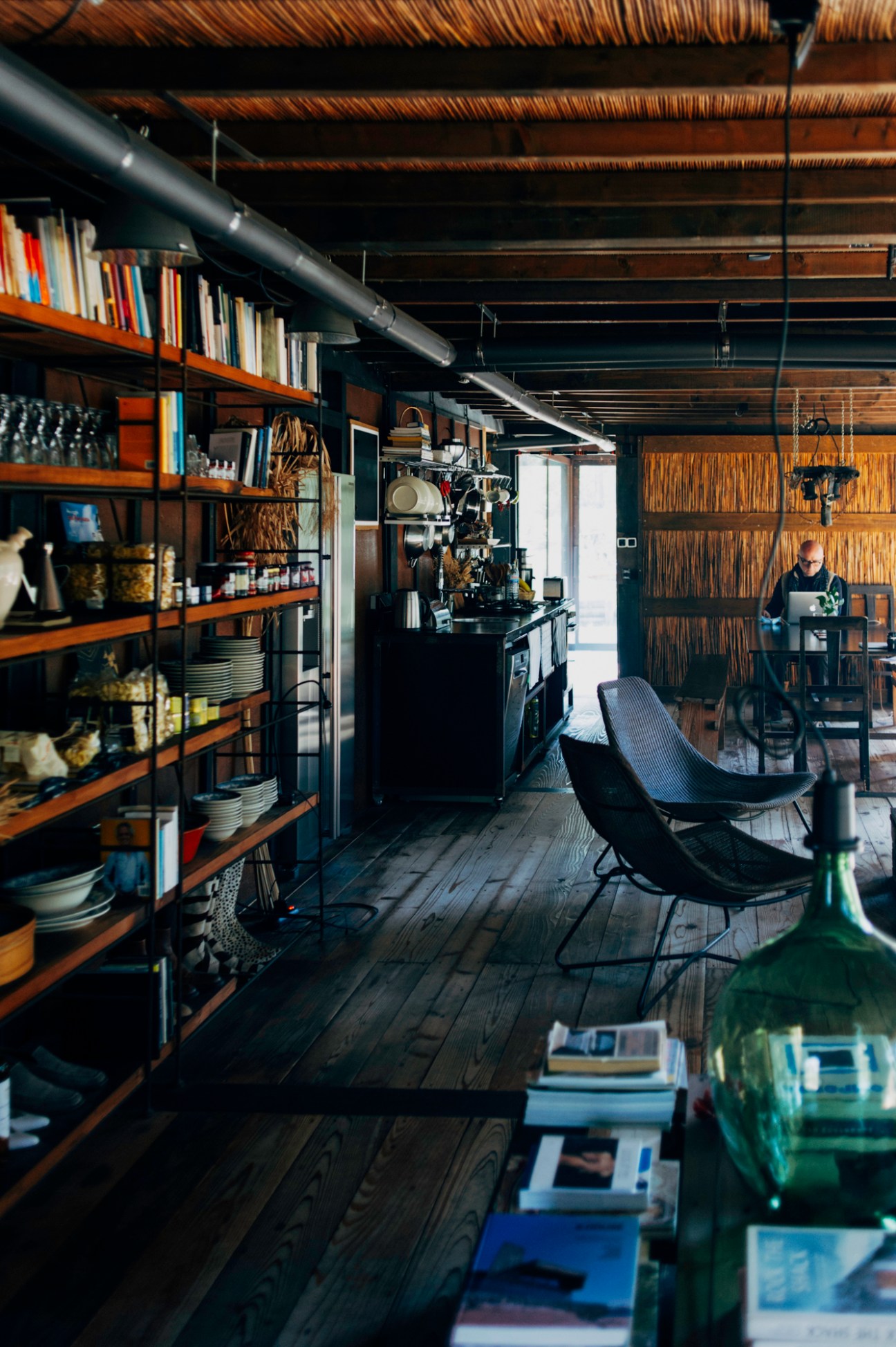 Modern kitchen and dining area with exposed wooden beams, industrial shelving, and contemporary seating