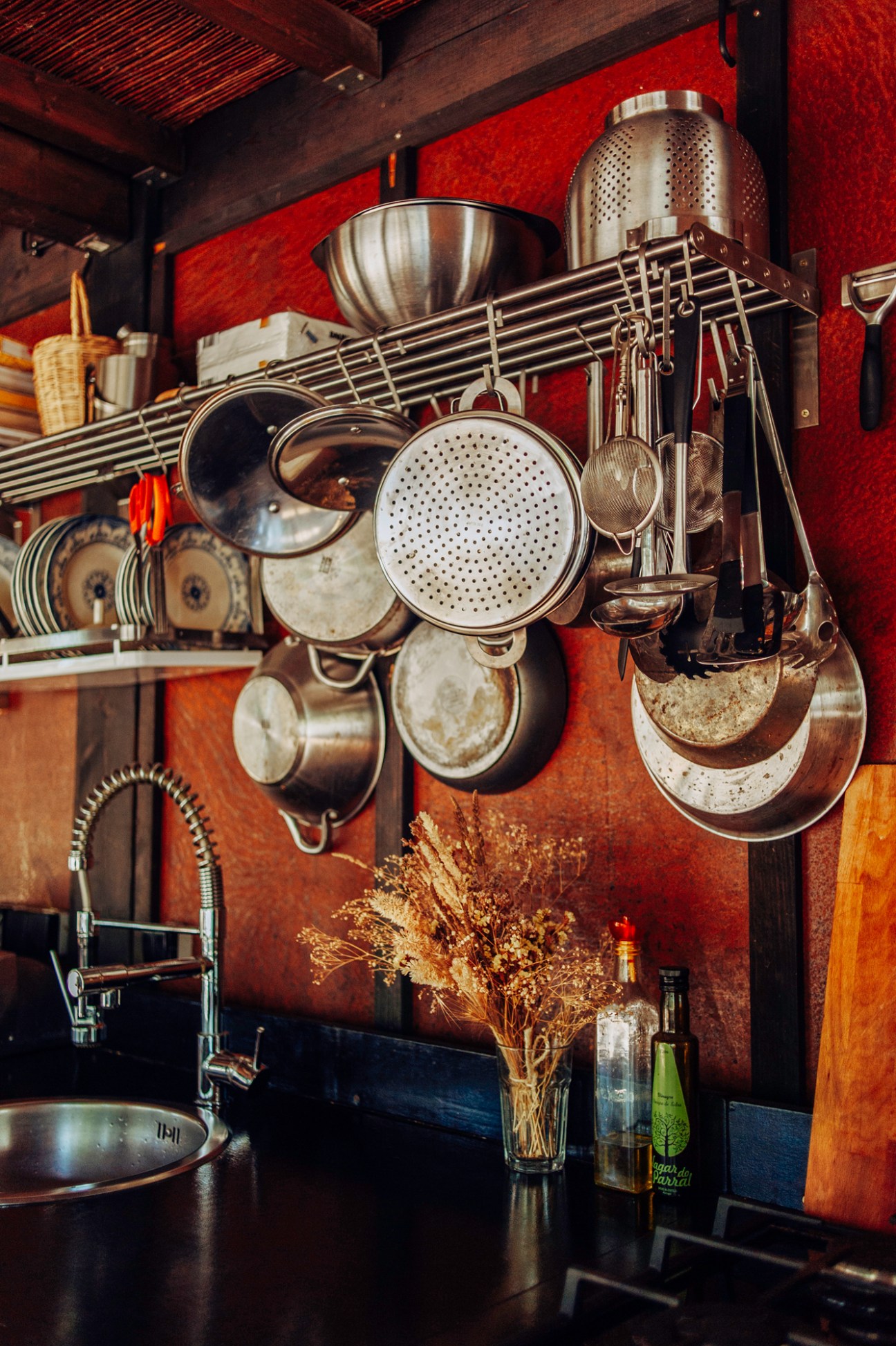 Kitchen shelving unit with hanging pots, pans, bowls, and cooking utensils arranged on wire racks