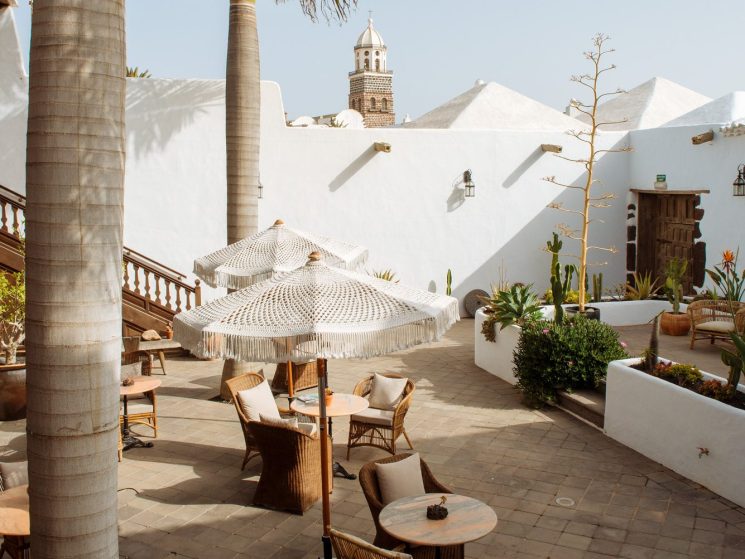 Outdoor terrace at Hotel Palacio Ico with wicker furniture, palm trees, and white colonial architecture