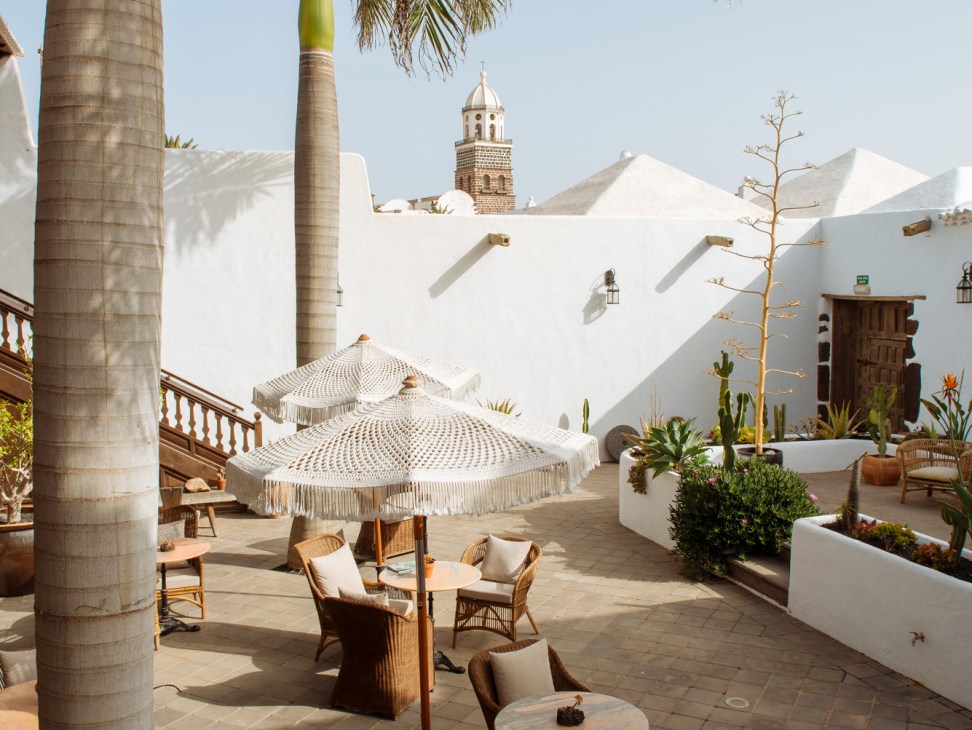 Outdoor terrace at Hotel Palacio Ico with wicker furniture, palm trees, and white colonial architecture