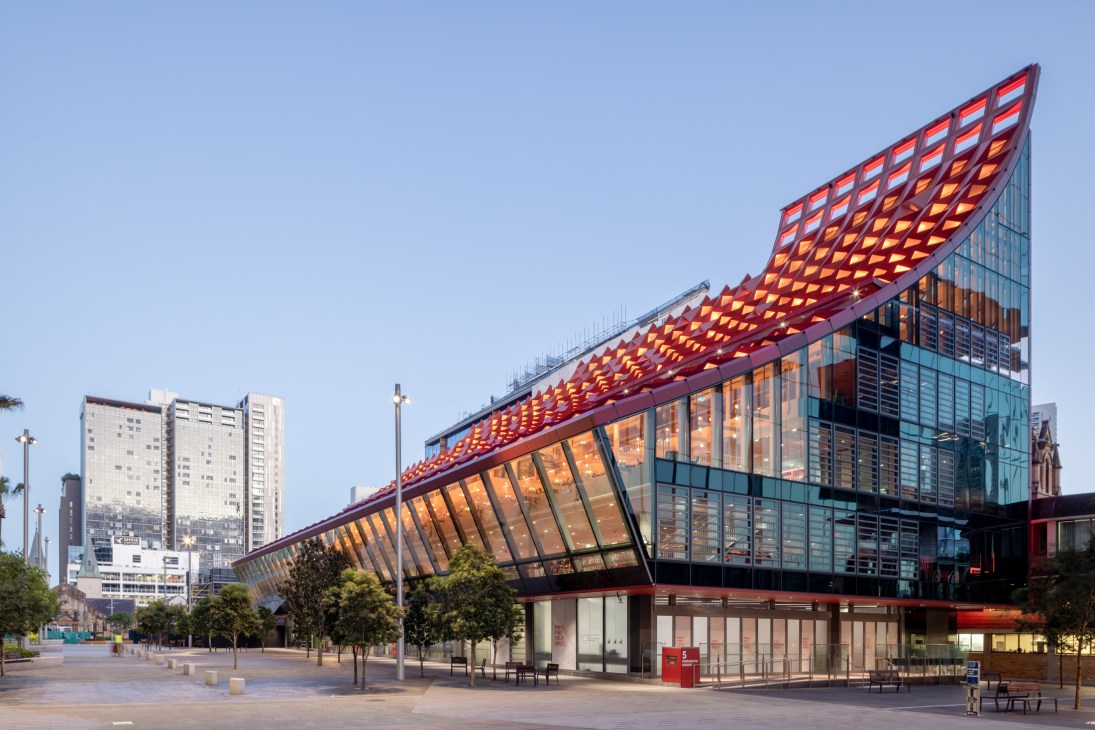 Modern library building with distinctive curved red latticed roof and glass facade in urban setting