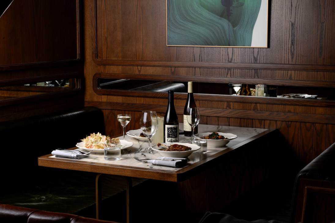 Elegant restaurant table setting with wine bottle, glasses, and plates in wood-paneled dining room