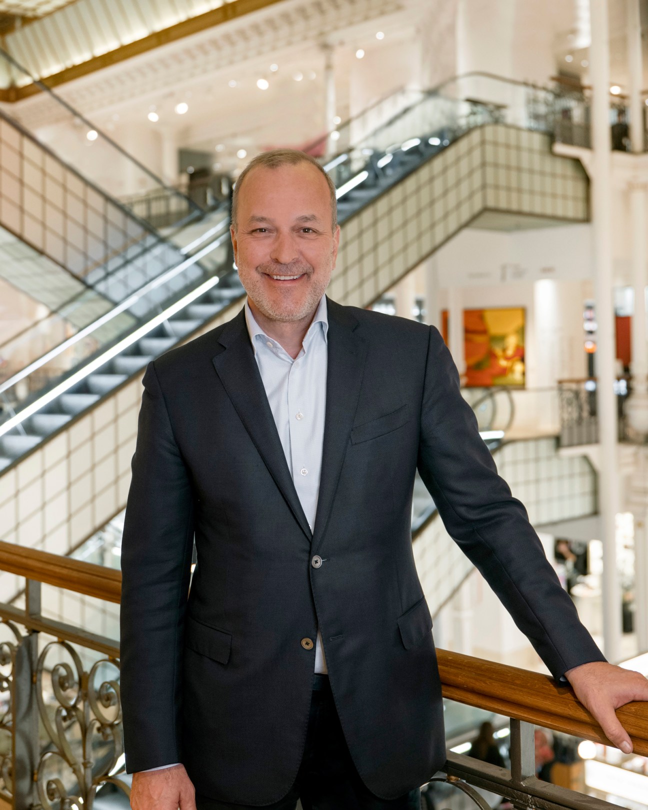 Patrice Wagner smiling in a dark suit jacket standing on a curved staircase in an upscale interior