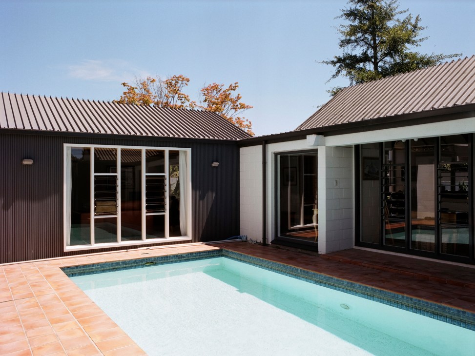 Modern house courtyard with swimming pool surrounded by concrete block walls and large windows