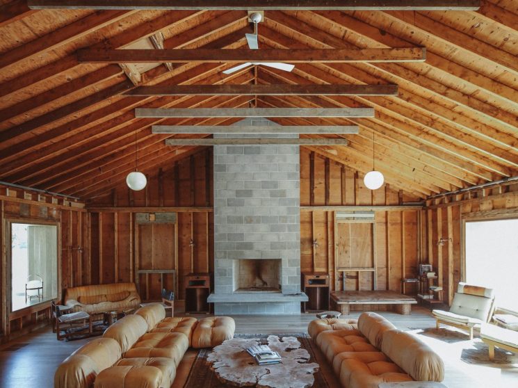Interior view of a living room with stone fireplace and wooden slatted ceiling.