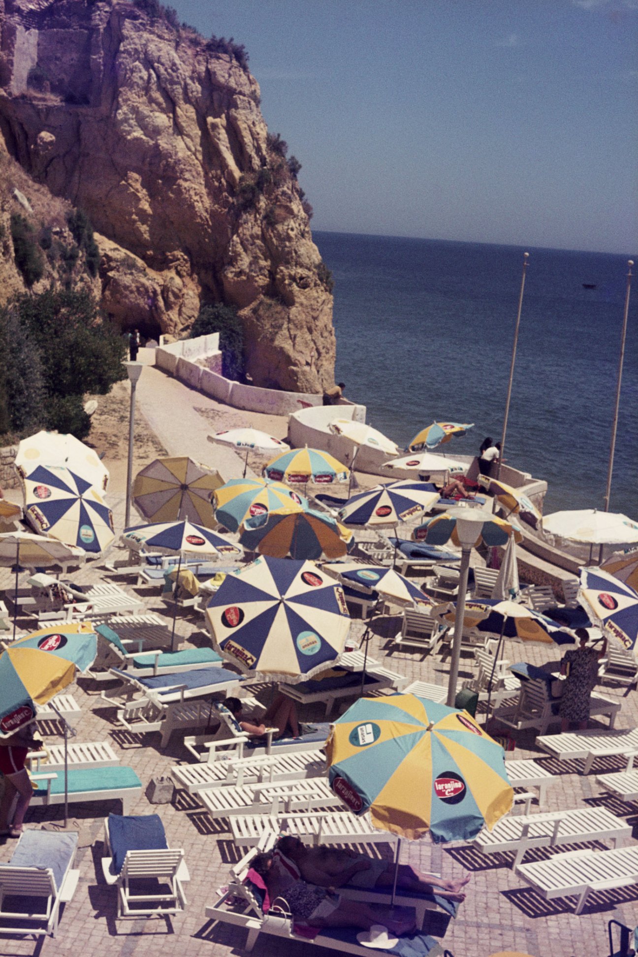 Beach scene with colorful umbrellas, lounge chairs and people at a Mediterranean coastal resort
