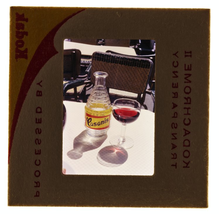A Kodak film slide showing a vintage photograph of a Casanis bottle and wine glass on a white table outdoors