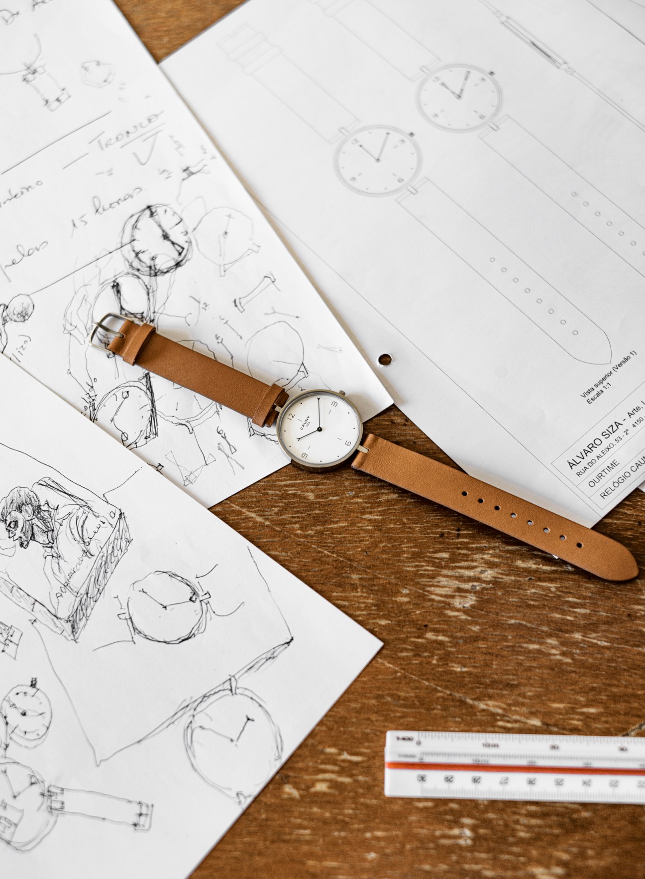 Cauny 3 Siza watch with white dial and brown leather strap on wooden surface with design sketches