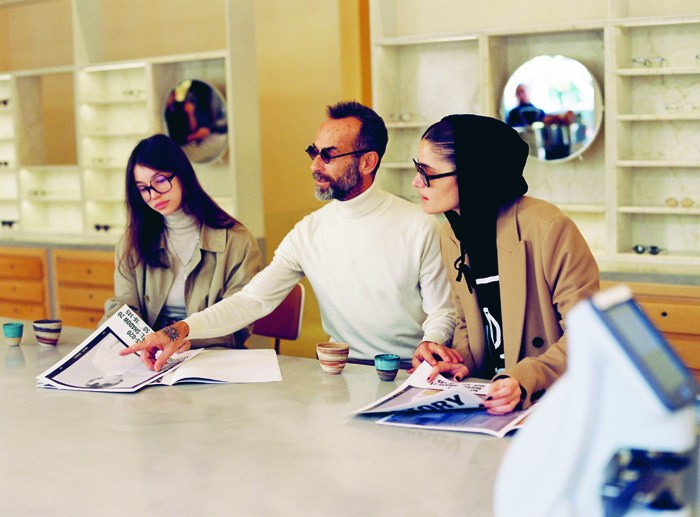 Three customers examining eyeglass frames at Glassworks optician in Tel Aviv