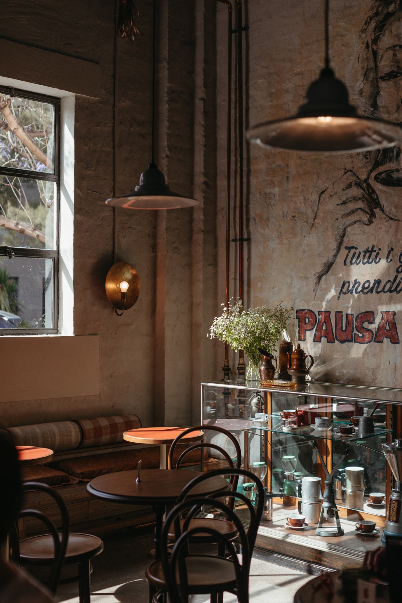 Interior of Genovese Coffee House featuring pendant lights, bentwood chairs, glass display case and brick walls