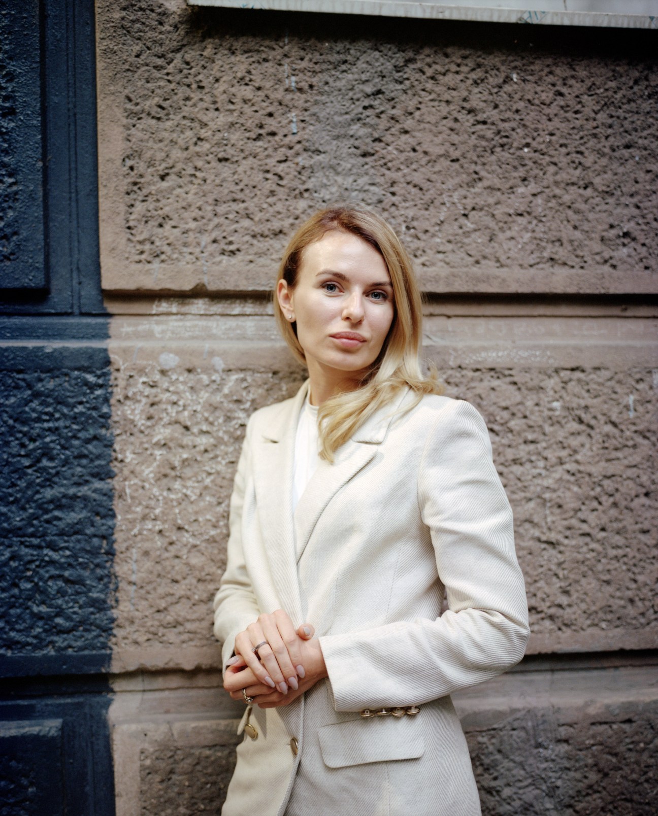 Ukrainian MP Lesia Vasylenko in a cream blazer standing against a textured stone wall