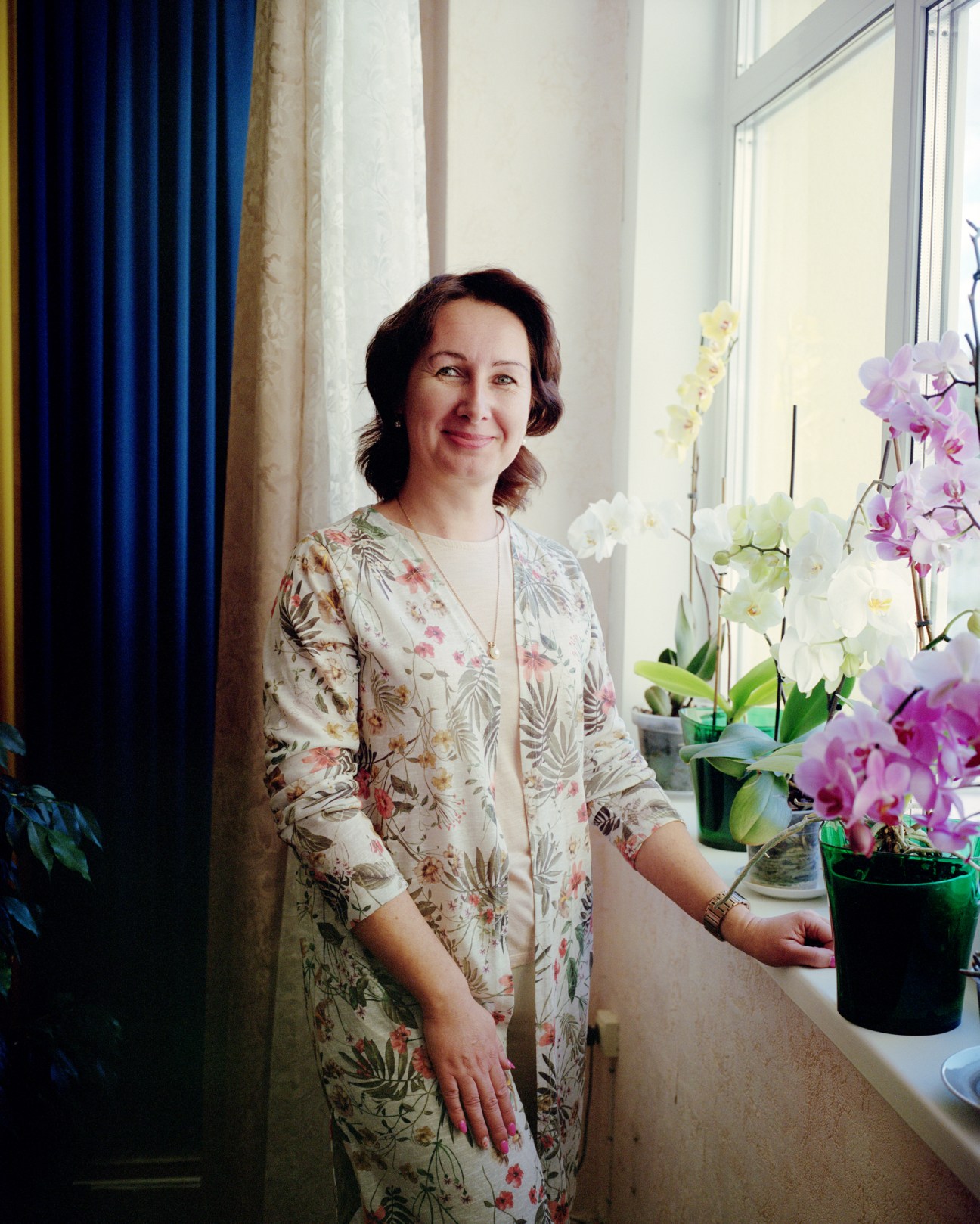 Nataliia Ivanytska, school principal, standing next to her orchid flowers by a window