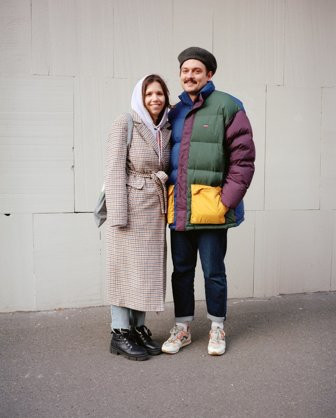 Couple walking together wearing winter coats near modern buildings