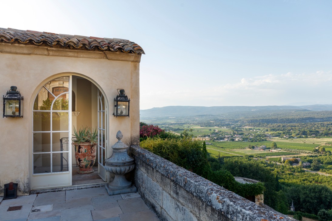 French hotel terrace with arched doors, stone balustrade overlooking countryside valley view