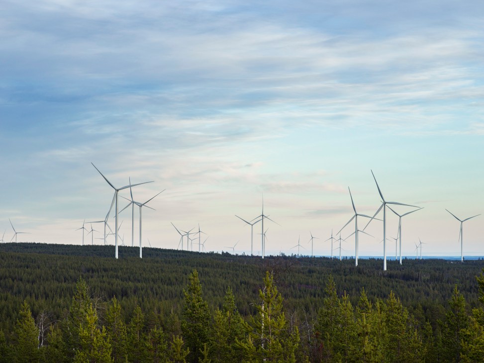 Row of tall white wind turbines against dramatic cloudy sky