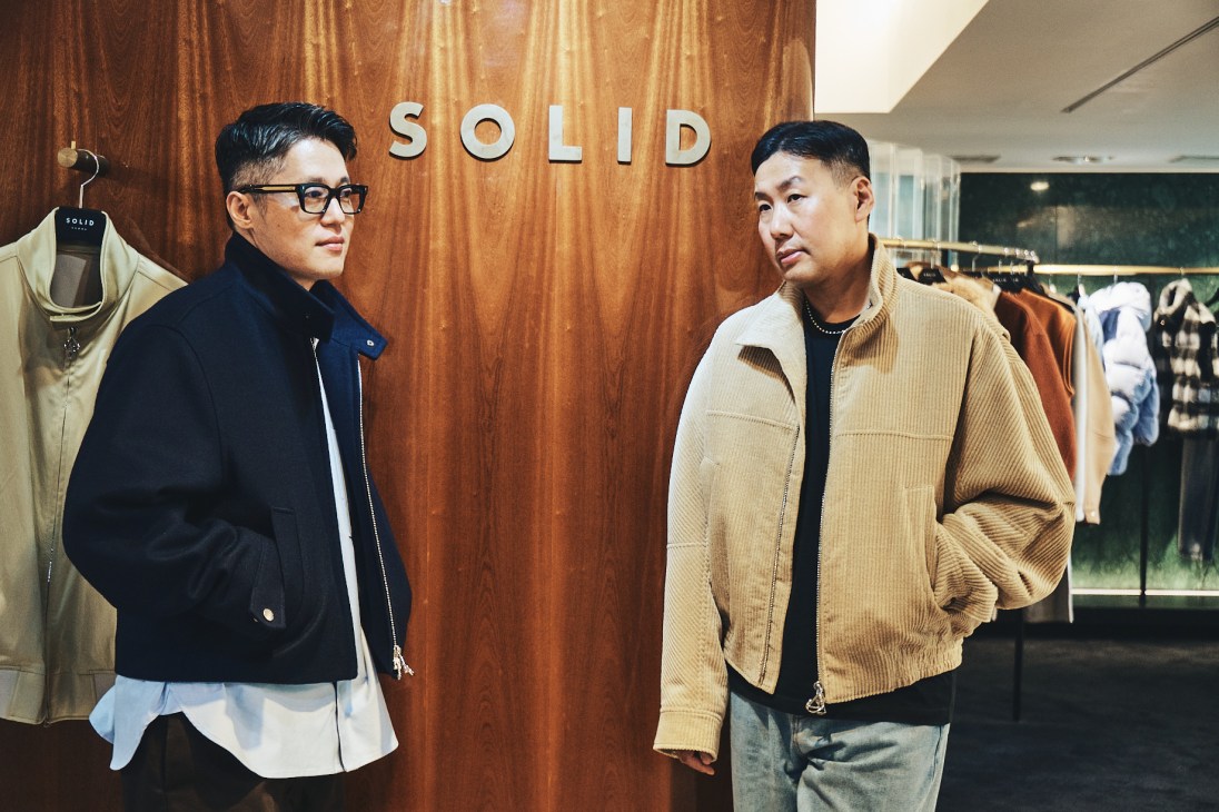 Two men standing in front of a wooden wall with 'SOLID' lettering in a clothing store