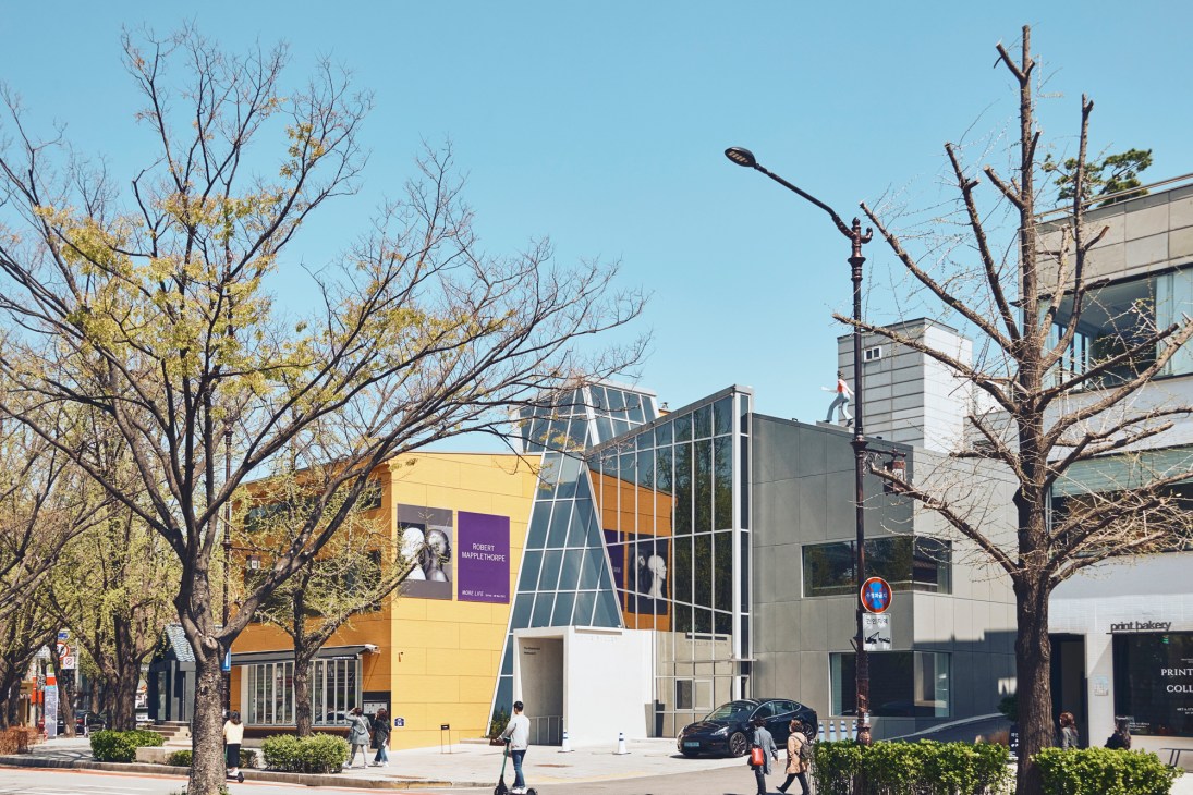 Exterior of Kukje Gallery, a modern building with yellow and dark paneling on a street with bare trees.