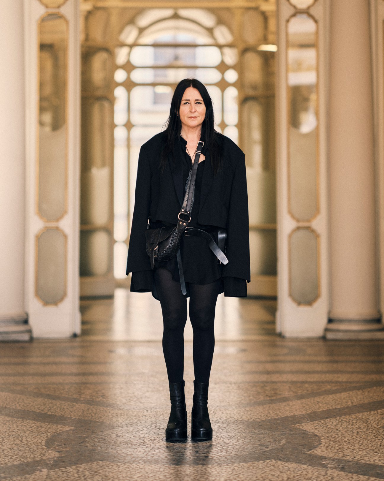 An Vandevorst, head of fashion design at Polimoda, standing in ornate hallway wearing all black outfit