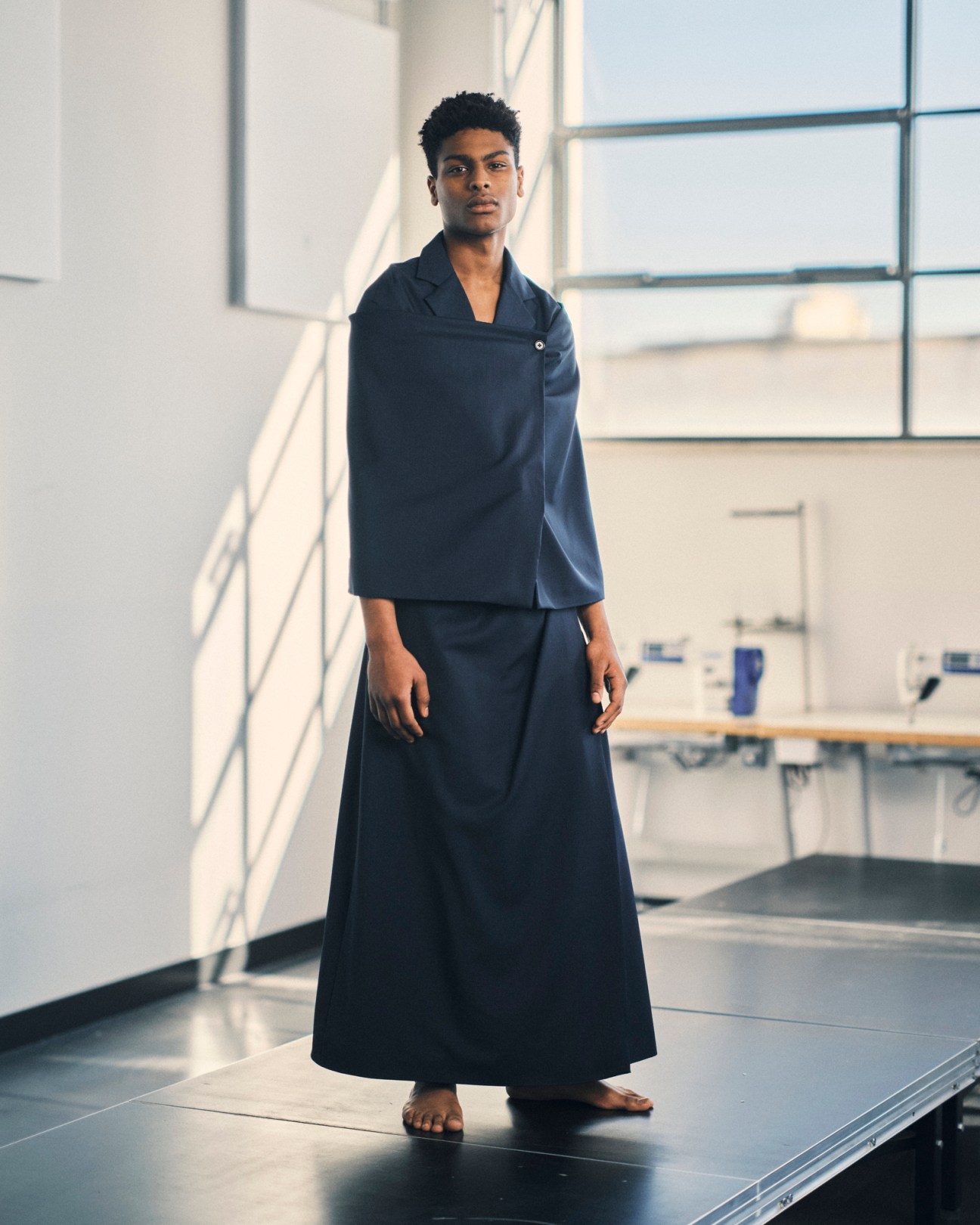 Person wearing navy blue outfit by Alvaro Barrera Lozano in modern interior space