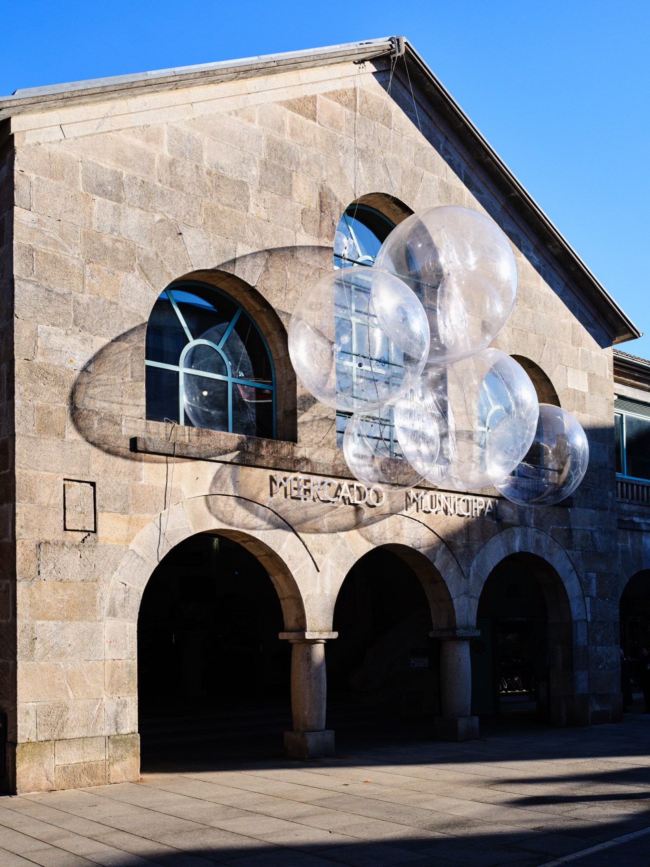 Historic stone building with arched openings and large transparent spherical art installation