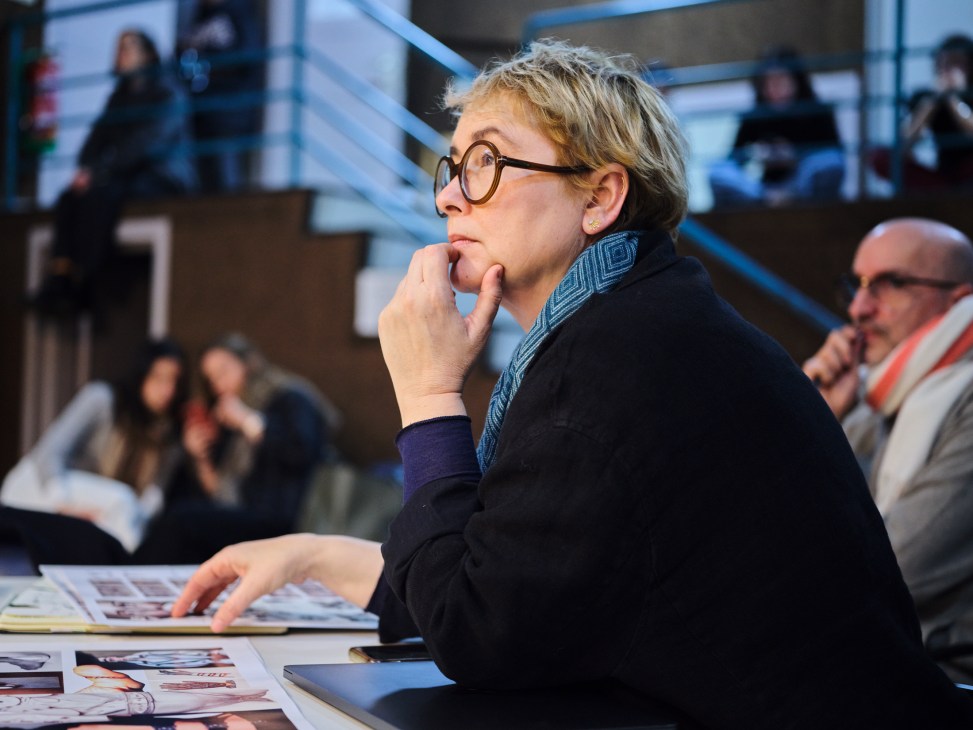 Fashion design course leader Lola Dopico sitting at a table with documents and materials