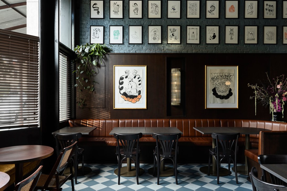 Interior of Poodle Upstairs bar showing leather banquette seating, dark wood tables and gallery wall of framed artwork