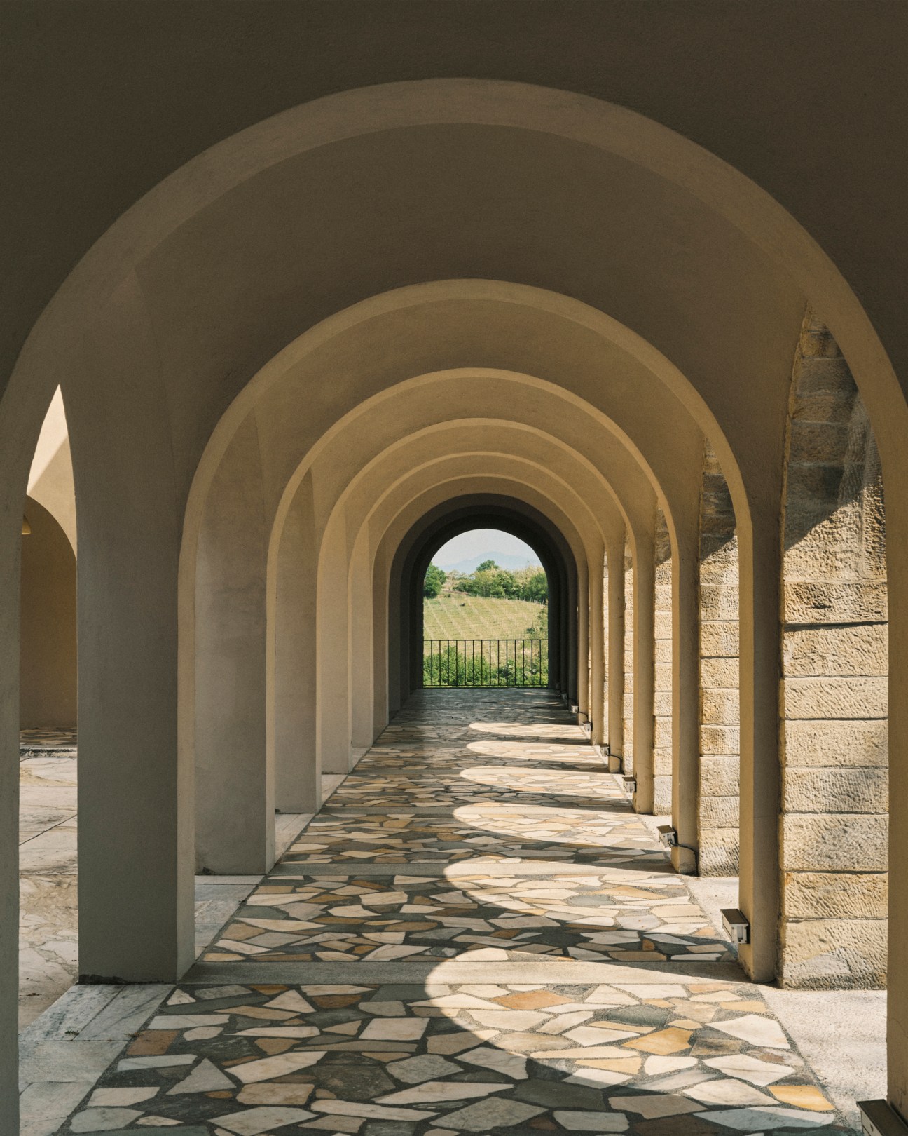 Stone archway corridor with arched ceiling leading to garden view at Villa Ottolenghi