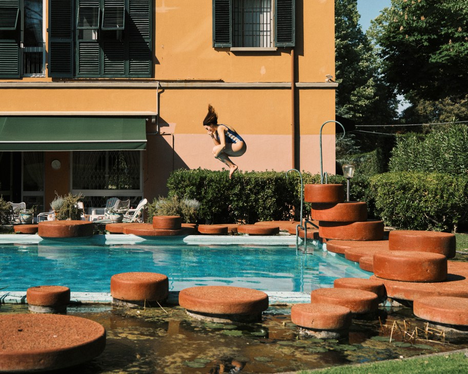 Swimming pool surrounded by circular red Verona marble slabs and water lily pond at Villa La Terraza with person diving