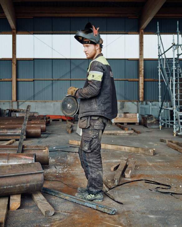 Worker in welding gear at a port in Umeå holding grinding disc.