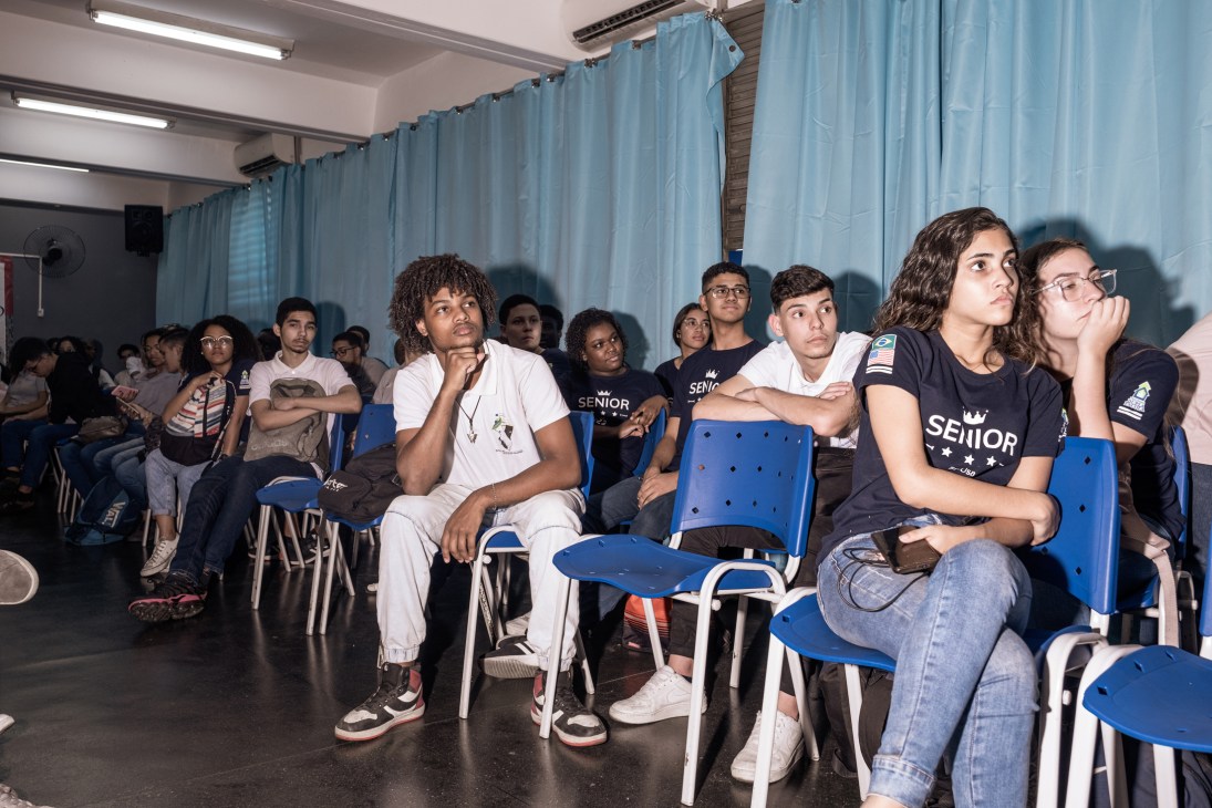 Students at Carlos Drummond de Andrade school in Rio sitting in blue plastic chairs looking attentively forward