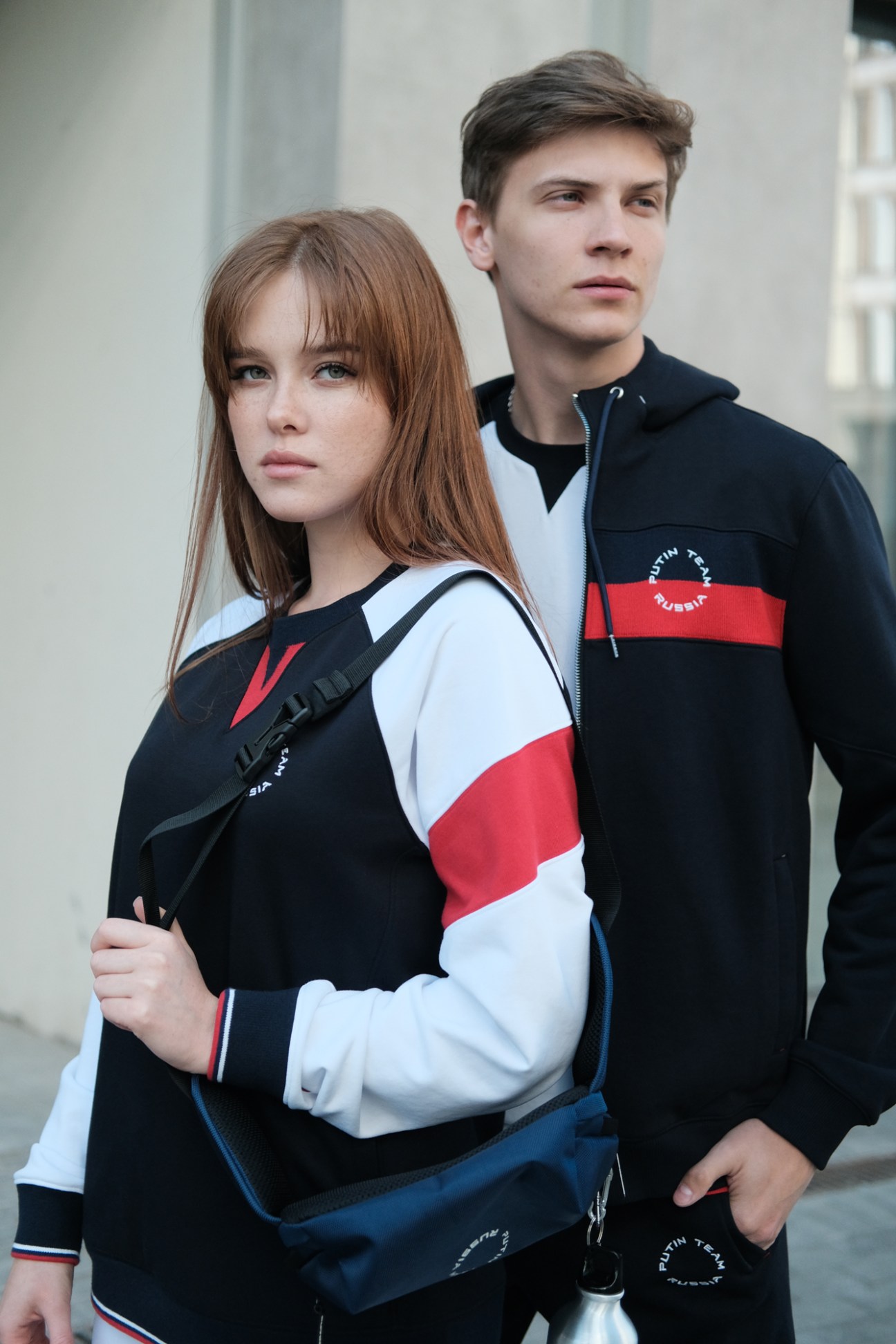 Two young people wearing Putin Team Russia branded sportswear in navy, white and red colors