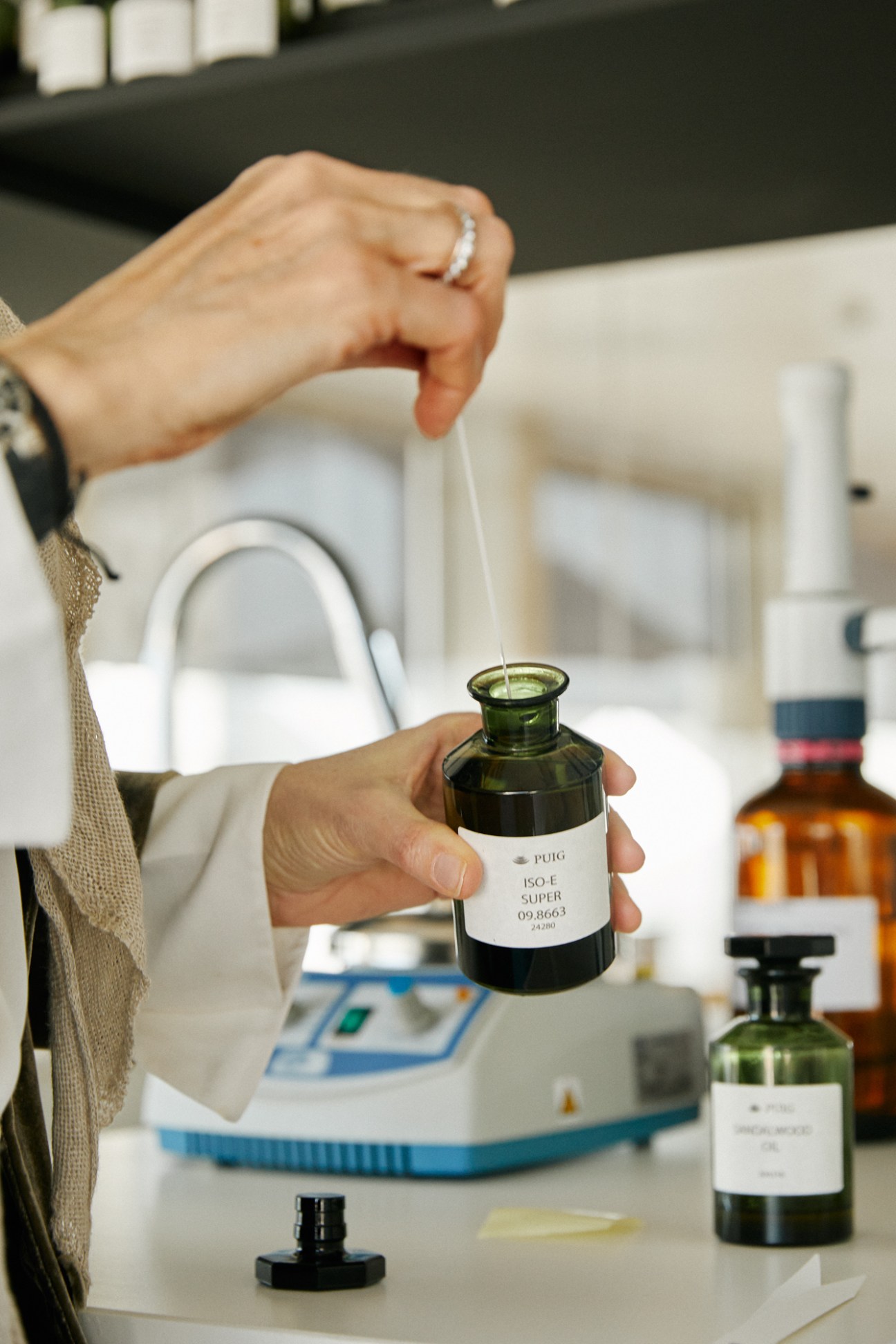 A perfumer testing fragrances in the modern lab space with cream sofas and slatted-wood dividers