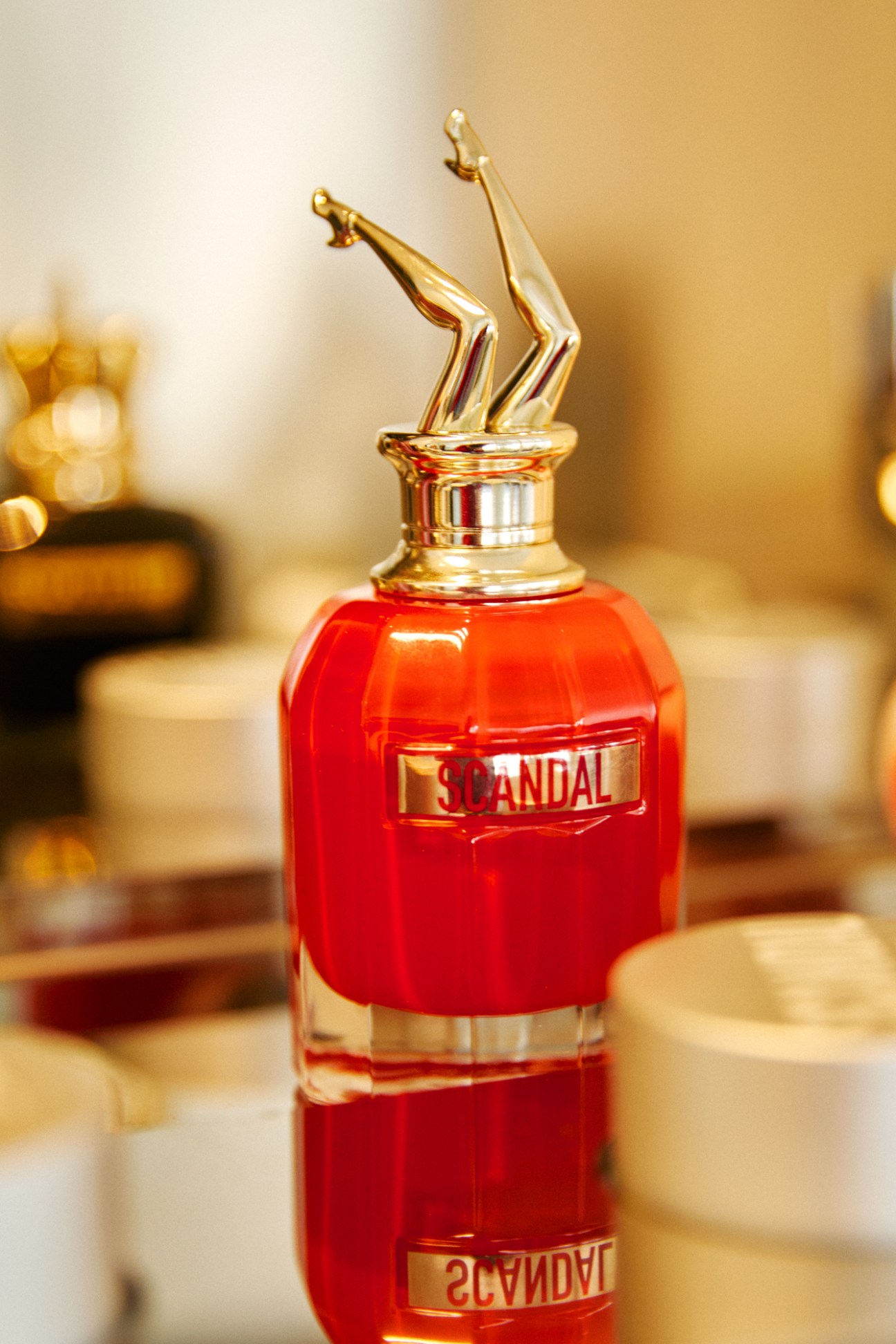 A red perfume bottle with gold cap displaying the Scandal by Jean Paul Gaultier label