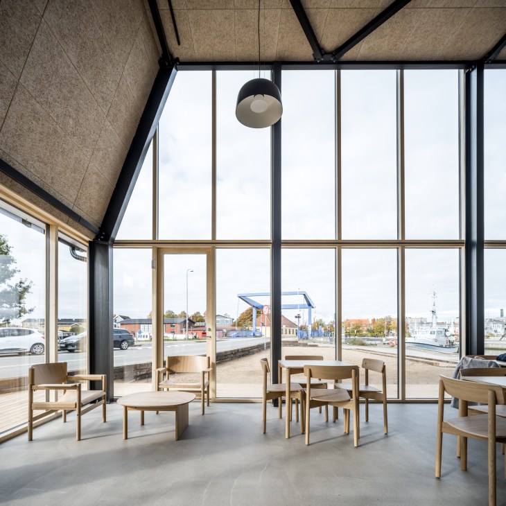Interior of Braunstein Taphouse showing light wood furniture, floor-to-ceiling windows, and harbor view