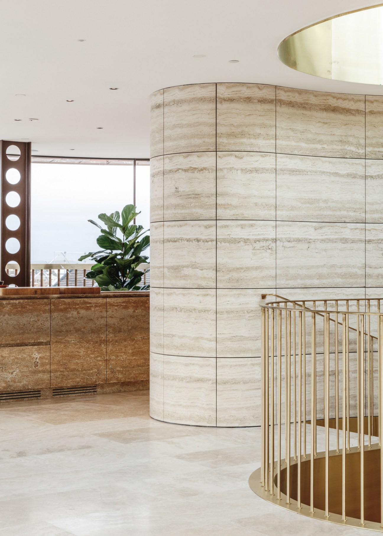 Elegant hotel lobby interior with curved travertine walls, brass railings, and modern minimalist design