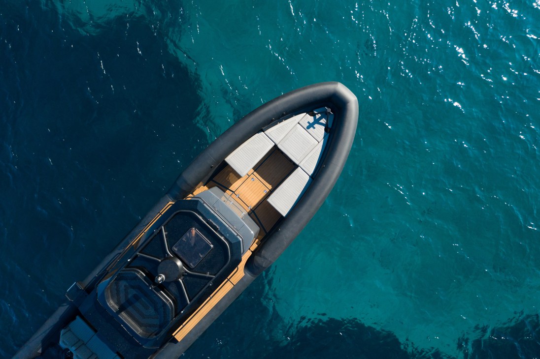 Aerial view of a sleek motorboat with dark hull cutting through turquoise water