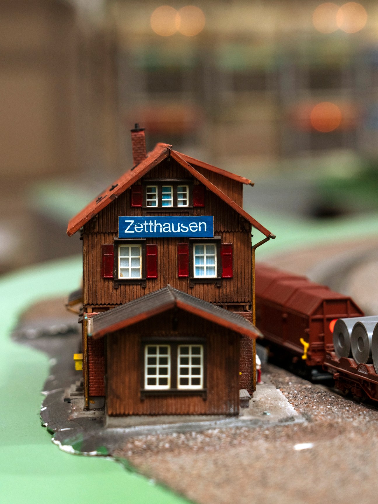 Miniature wooden railway station building with red roof and shutters labeled Zetthausen on model train set