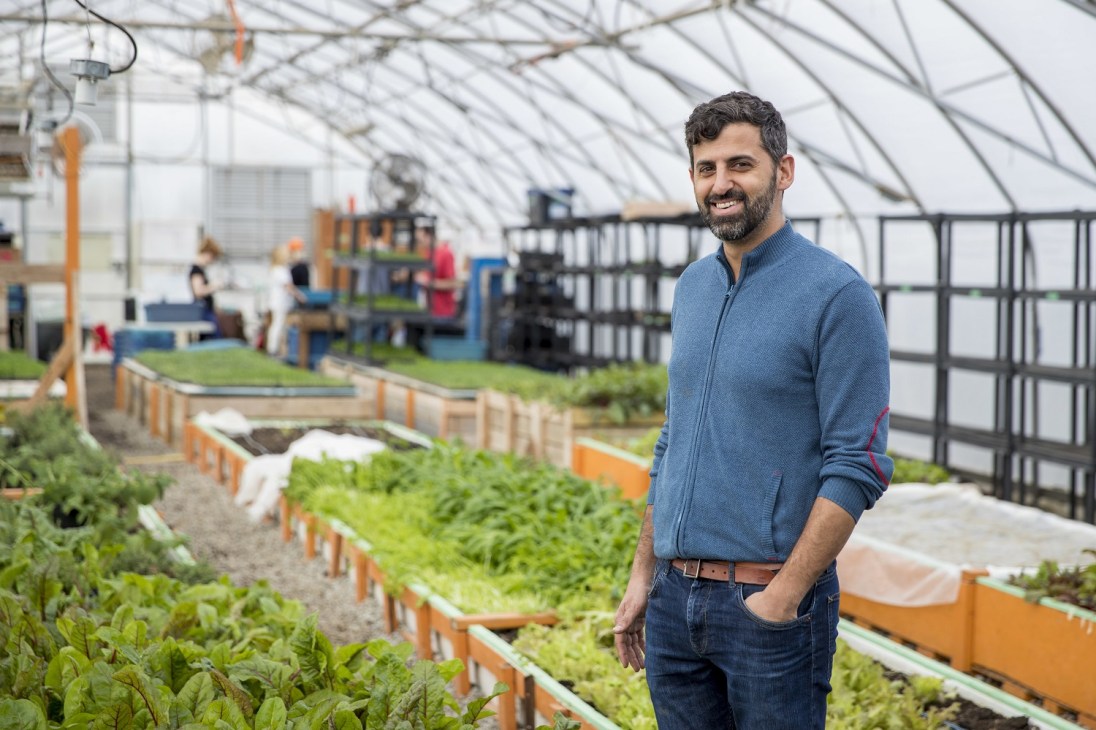 Ran Goel, founder and CEO of Fresh City Farms, standing in an urban greenhouse surrounded by growing plants.